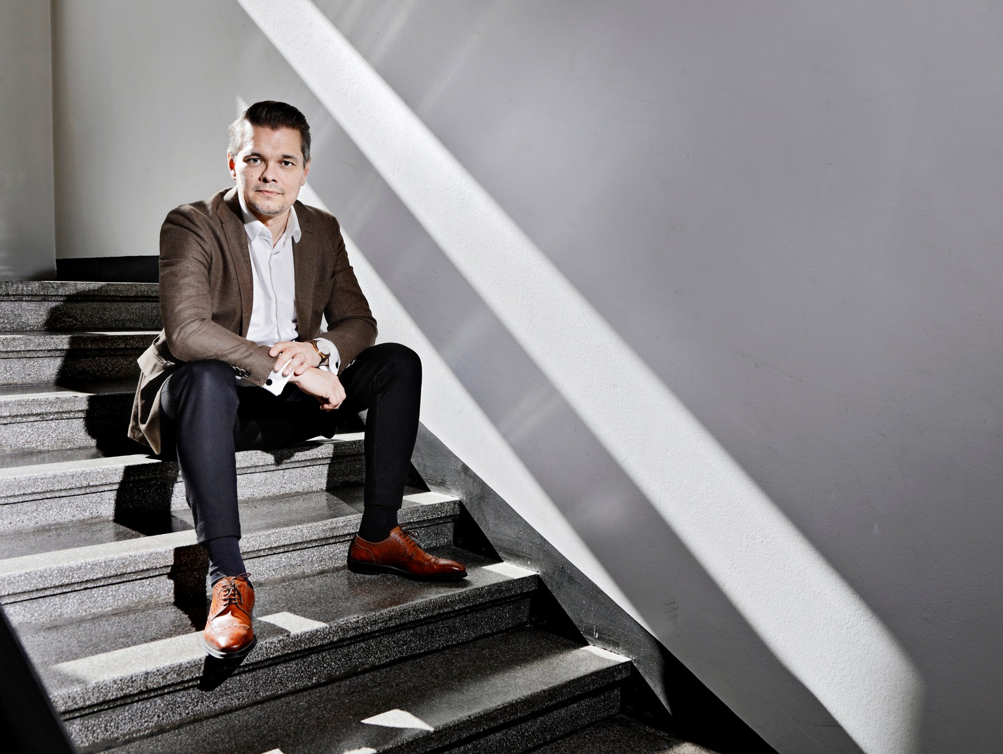 Mies istuu porraskäytävässä.